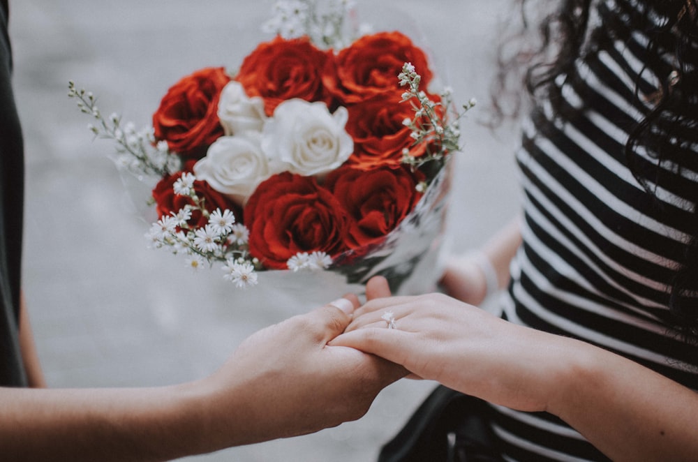 person holding red roses bouquet