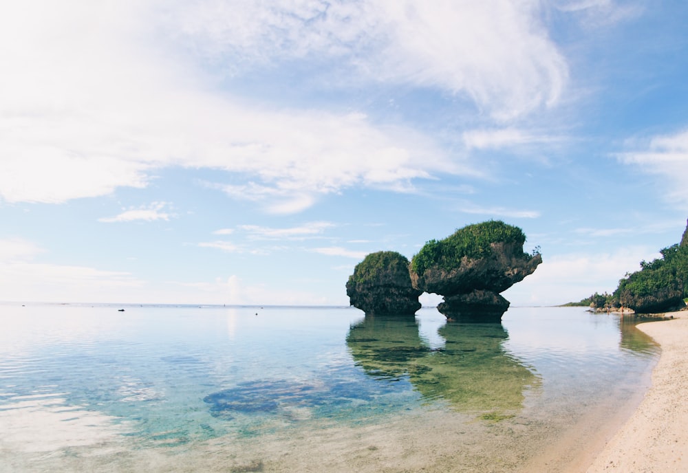 brown rock formation on body of water under blue sky during daytime