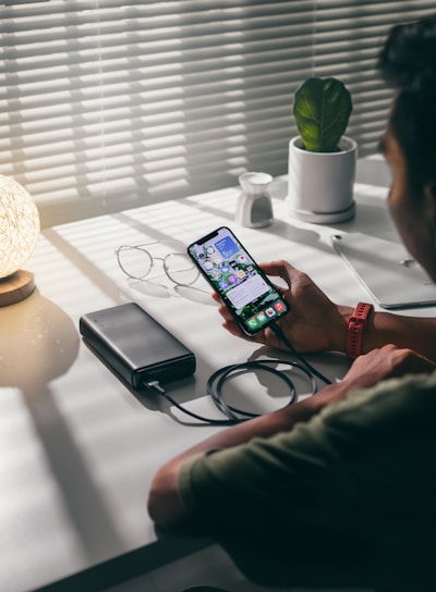 person holding black smartphone on white textile