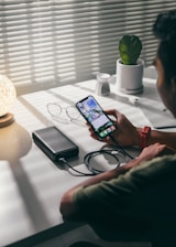 person holding black smartphone on white textile