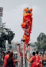 people walking on street with red dragon statue during daytime