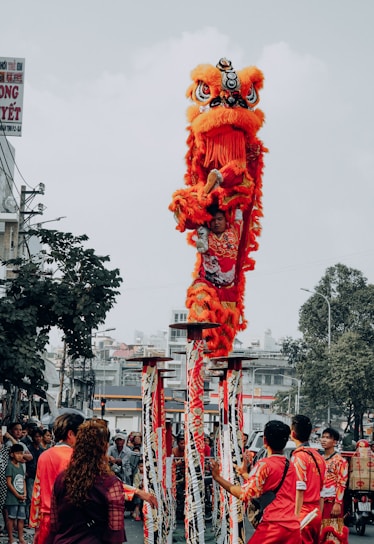 people walking on street with red dragon statue during daytime