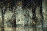 An abstract composition with dark, chaotic brushstrokes and splatters of color. The background suggests a forest with tall trees, obscured by a whirlwind of lines and random colorful elements.