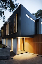 Modern minimalist house exterior with natural wood and stone textures.