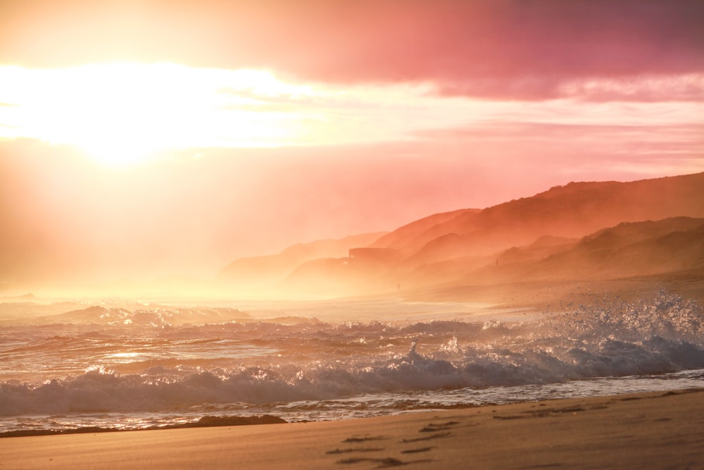 sea waves crashing on shore during sunset