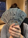 person holding fan of us dollar bill