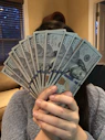 person holding fan of us dollar bill