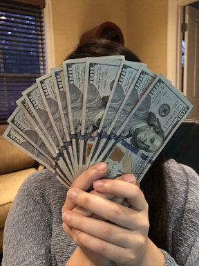 person holding fan of us dollar bill