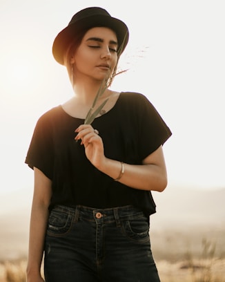 woman in black shirt and blue denim jeans holding white umbrella
