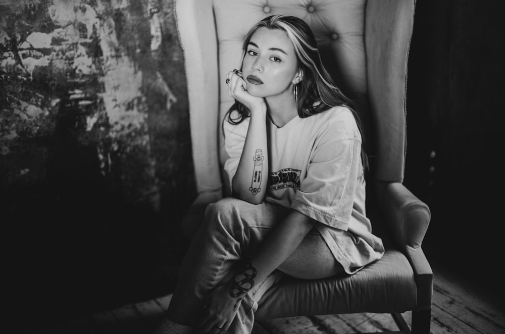 grayscale photo of woman in t-shirt sitting on sofa