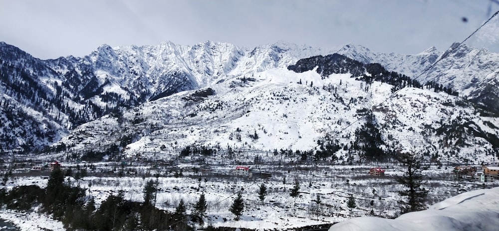 snow covered mountain near body of water during daytime