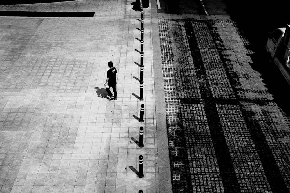 grayscale photo of man and woman walking on sidewalk