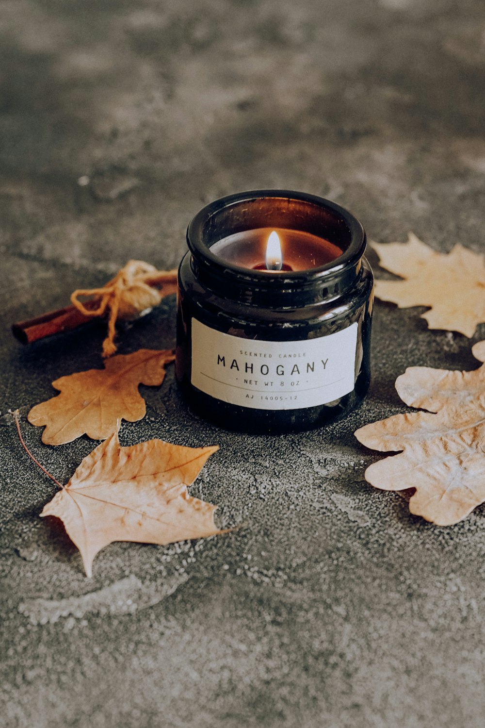 black candle holder with brown dried leaf on black surface