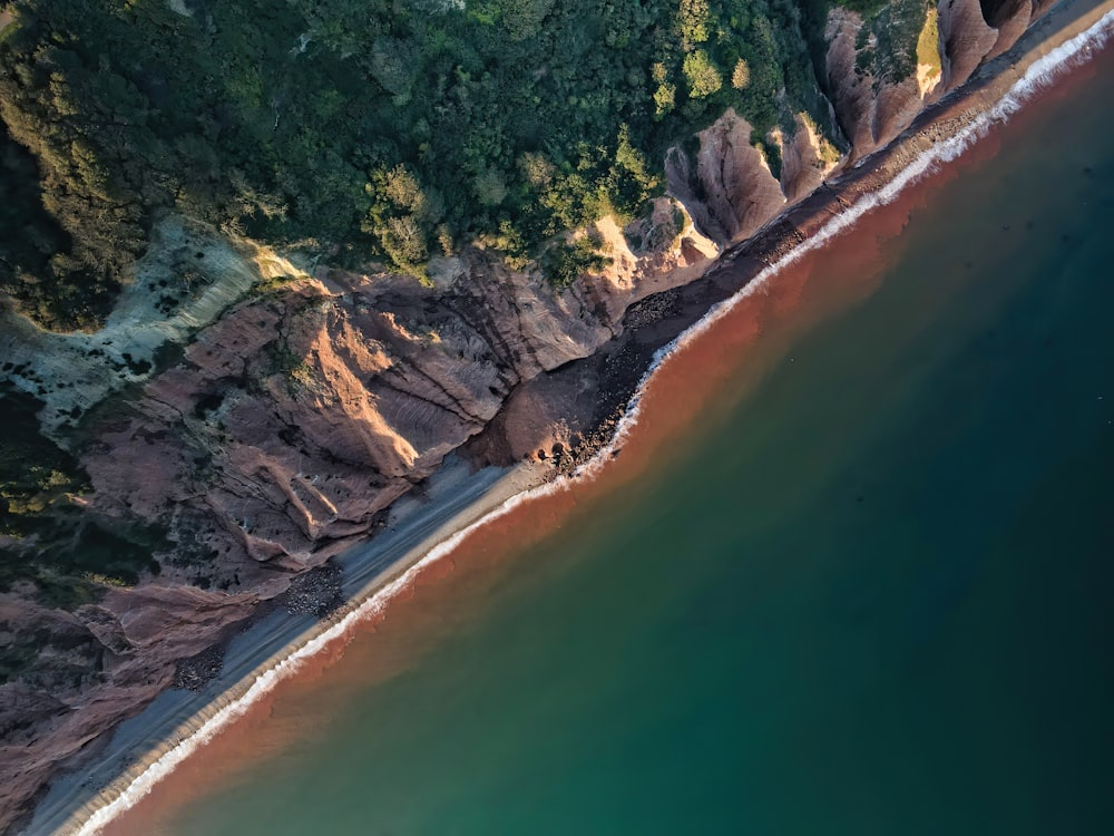 green and brown rocky mountain beside body of water during daytime