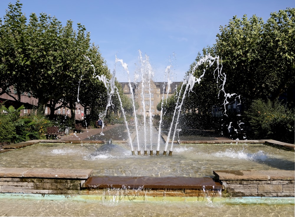 people sitting on bench near fountain during daytime