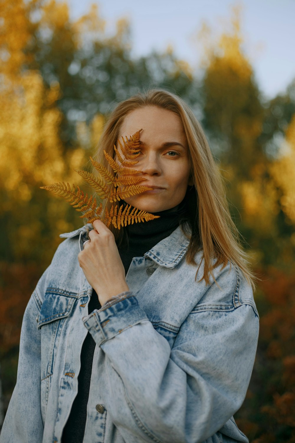 woman in blue denim jacket holding her hair