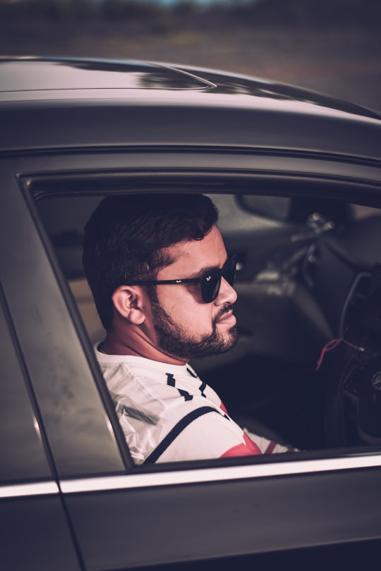 man in white and red stripe polo shirt wearing black sunglasses in Chikhli India