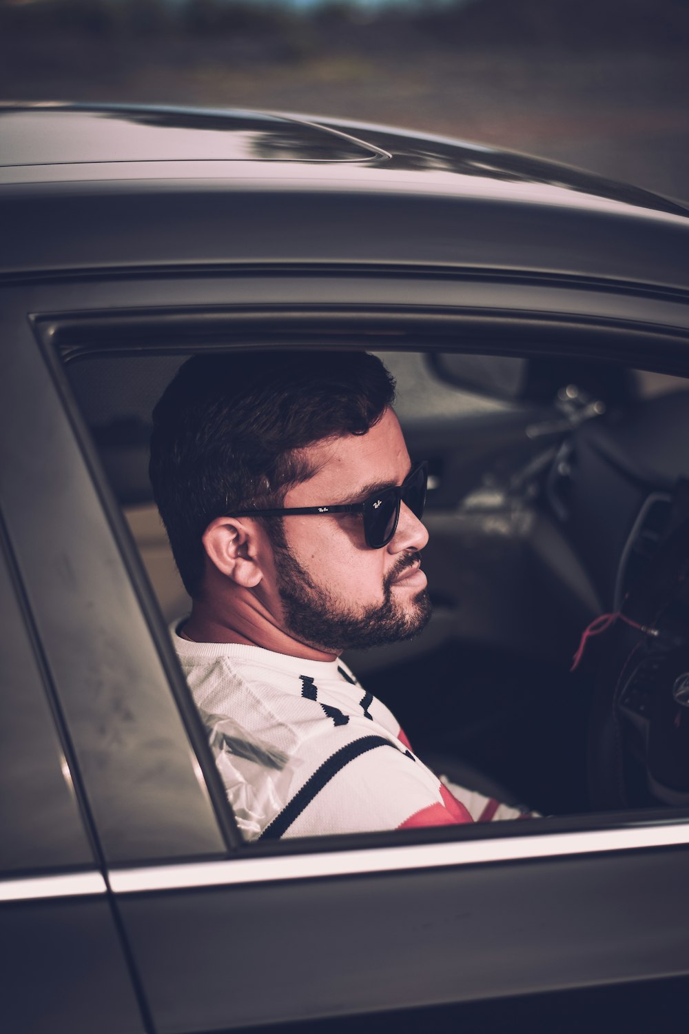 man in white and red stripe polo shirt wearing black sunglasses