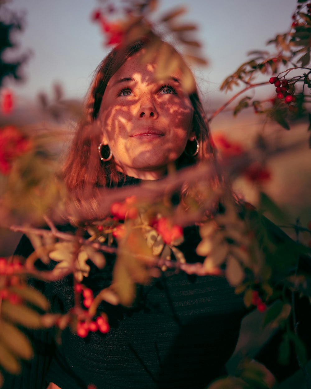 woman in black shirt standing near red flowers during daytime