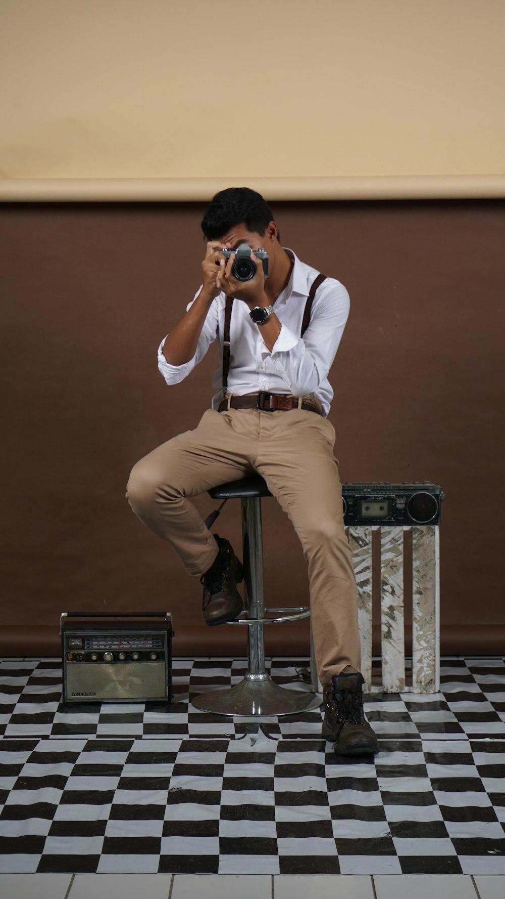 man in white dress shirt and brown pants sitting on black speaker