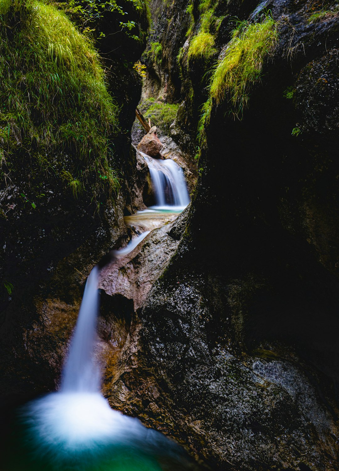 water falls between green moss covered rocks