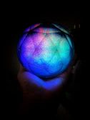 A mystical hand holding a radiant astrological globe with constellations shining brightly.
