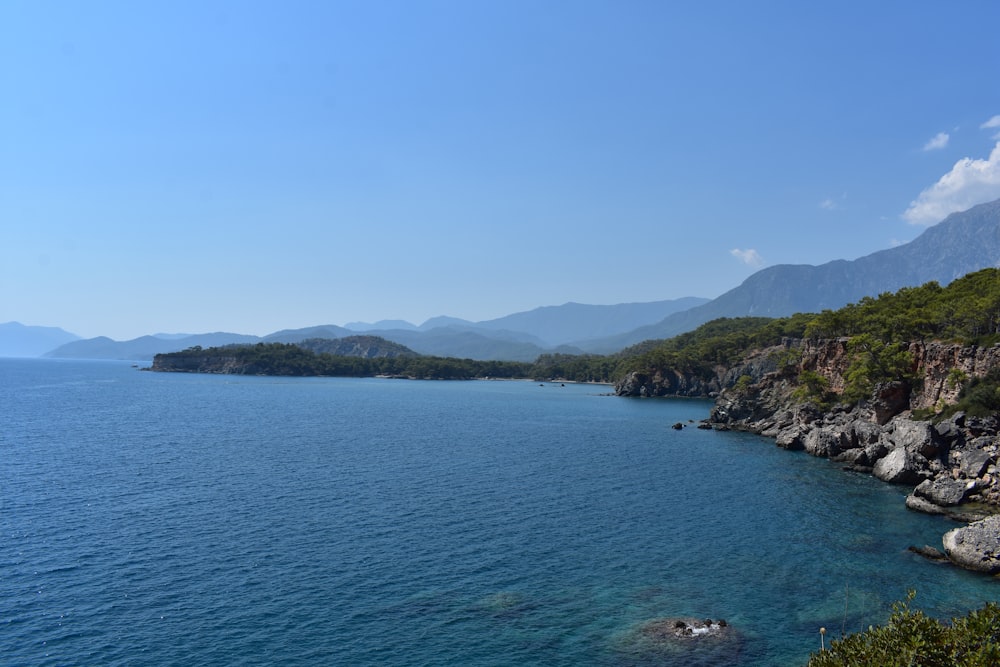 green mountains beside blue sea under blue sky during daytime