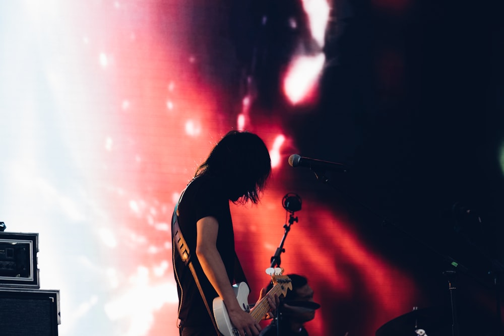 man in black and white t-shirt playing guitar