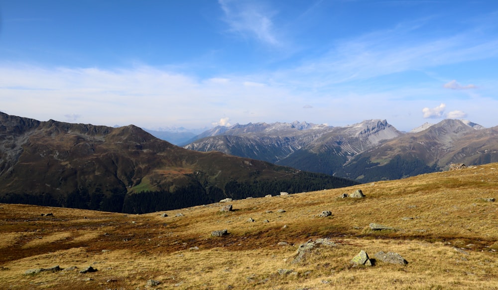 green grass field near mountains under blue sky during daytime