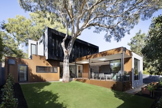 brown wooden house near green trees during daytime