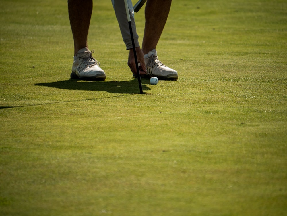 pessoa em sapatos nike brancos jogando golfe