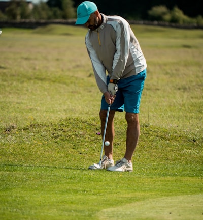 man in white long sleeve shirt and red cap playing golf during daytime