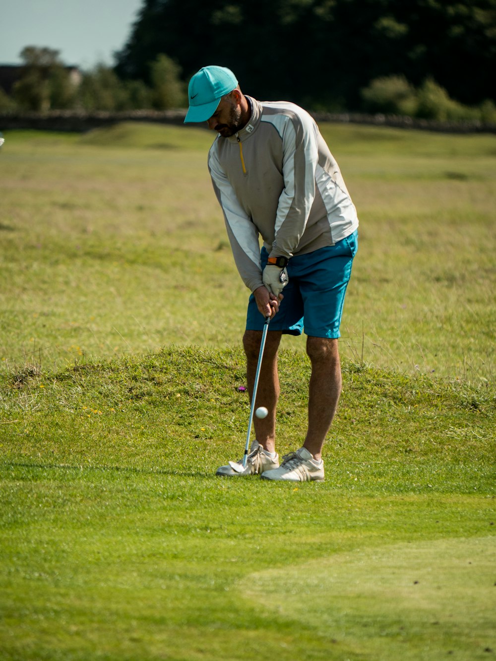 man in white long sleeve shirt and red cap playing golf during daytime