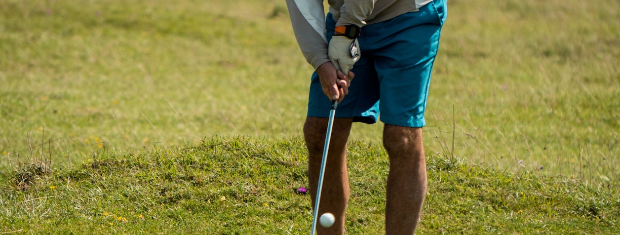man in white long sleeve shirt and red cap playing golf during daytime