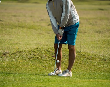 man in white long sleeve shirt and red cap playing golf during daytime