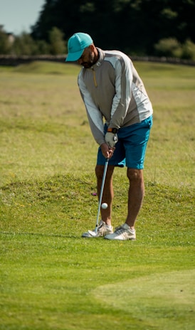 man in white long sleeve shirt and red cap playing golf during daytime