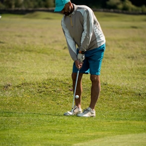 man in white long sleeve shirt and red cap playing golf during daytime