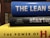 A stack of three books with colorful spines. The top book is blue with the title 'THE LEAN S'. The middle book has a black cover with the word 'startup' written on it and authors listed underneath. The bottom book is yellow, partially showing the title 'THE POWER OF H'. The books are stacked horizontally in a close-up view.