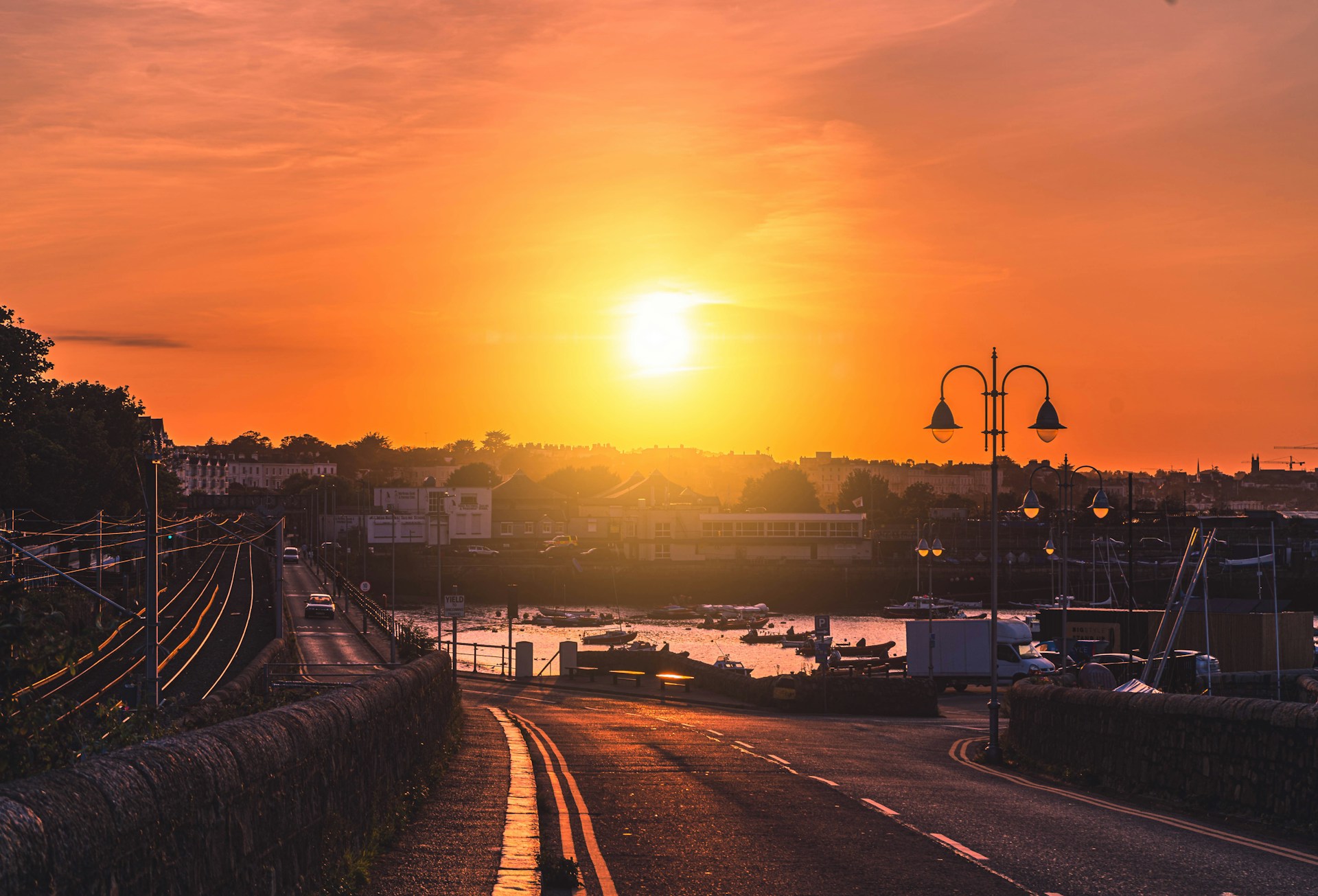 A vibrant sunset casting golden hues over a charming coastal village, with colorful boats resting in the harbor.