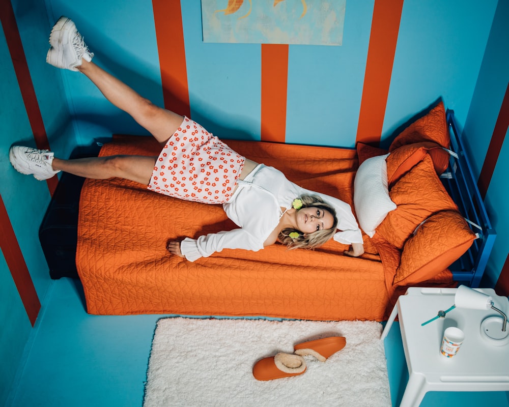 woman in white shirt lying on orange couch