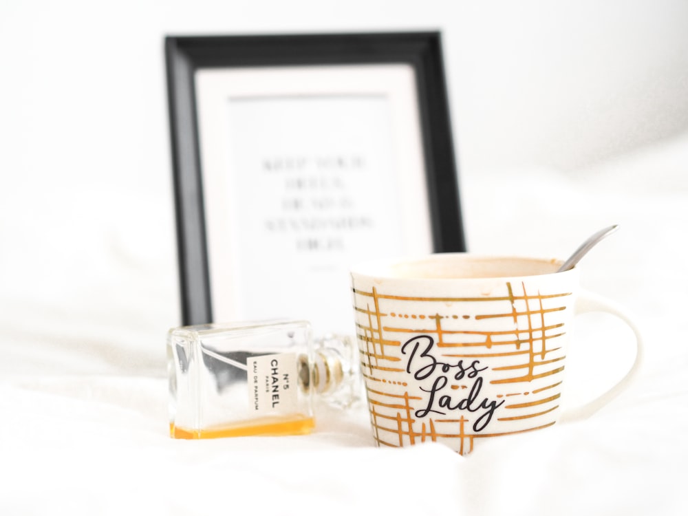 white and brown ceramic mug beside clear glass bottle