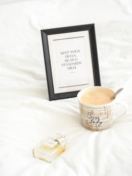 black wooden photo frame beside white and brown ceramic mug