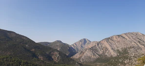 A serene mountain landscape with a clear blue sky and lush green valleys.