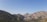 A serene mountain landscape with clear blue skies and rugged peaks in the distance.