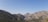 A serene mountain landscape with clear blue skies and rugged peaks in the distance.