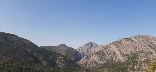 A serene mountain landscape with a winding trail under a clear blue sky.