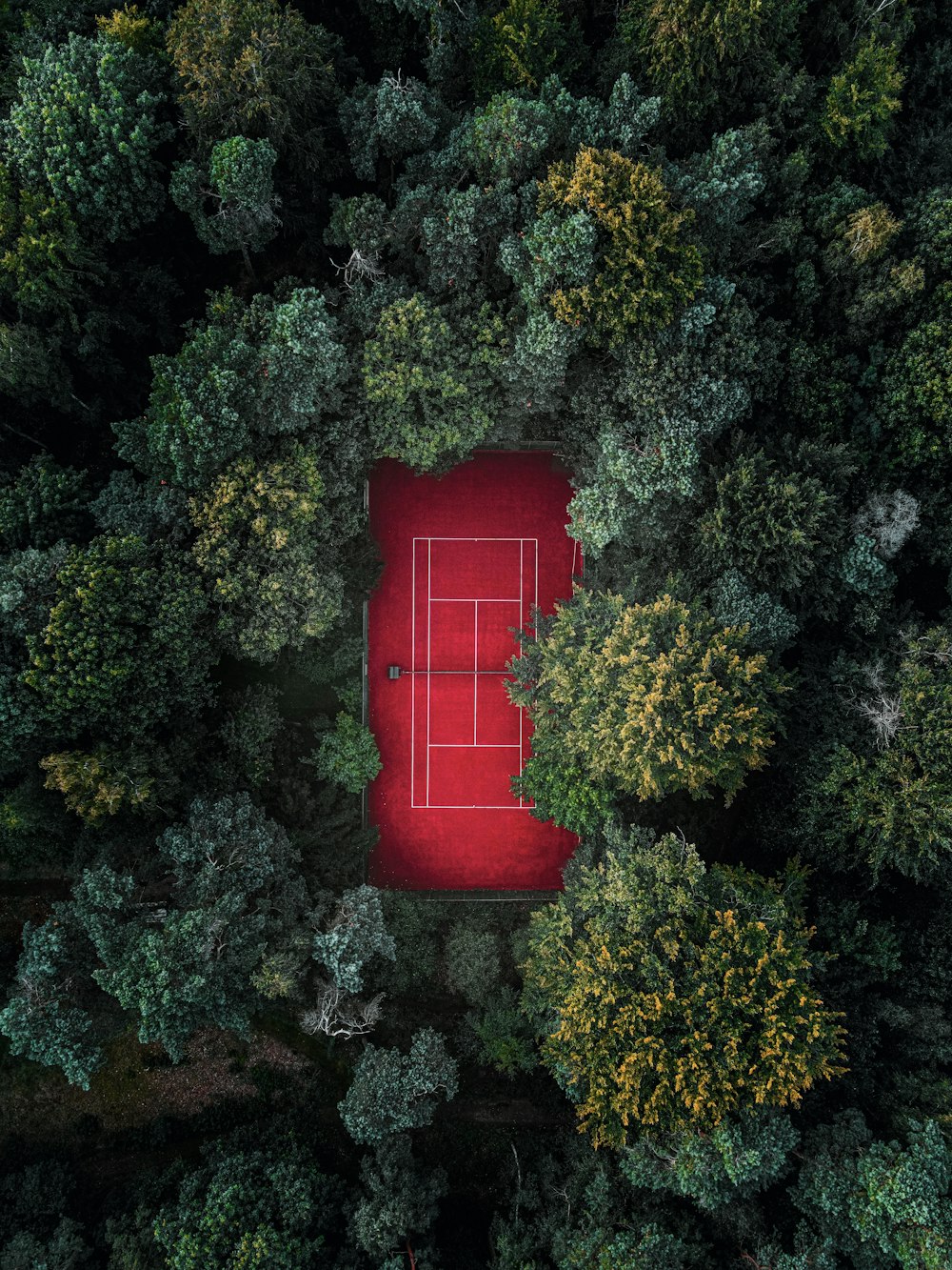 an aerial view of a tennis court surrounded by trees