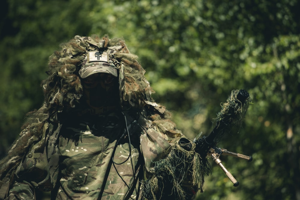 Hombre con uniforme de camuflaje verde y marrón sosteniendo un rifle