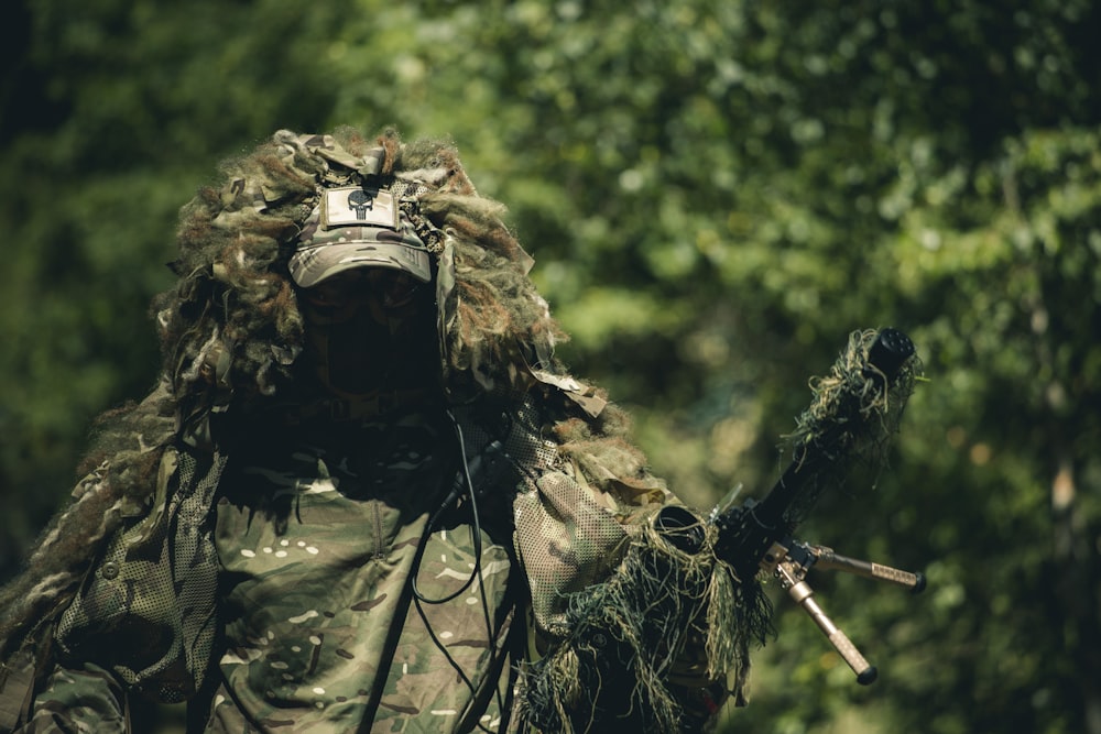 homme en uniforme de camouflage vert et marron tenant un fusil