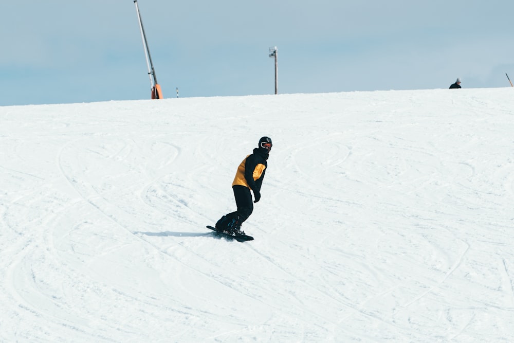 man in black jacket and black pants walking on snow covered ground during daytime